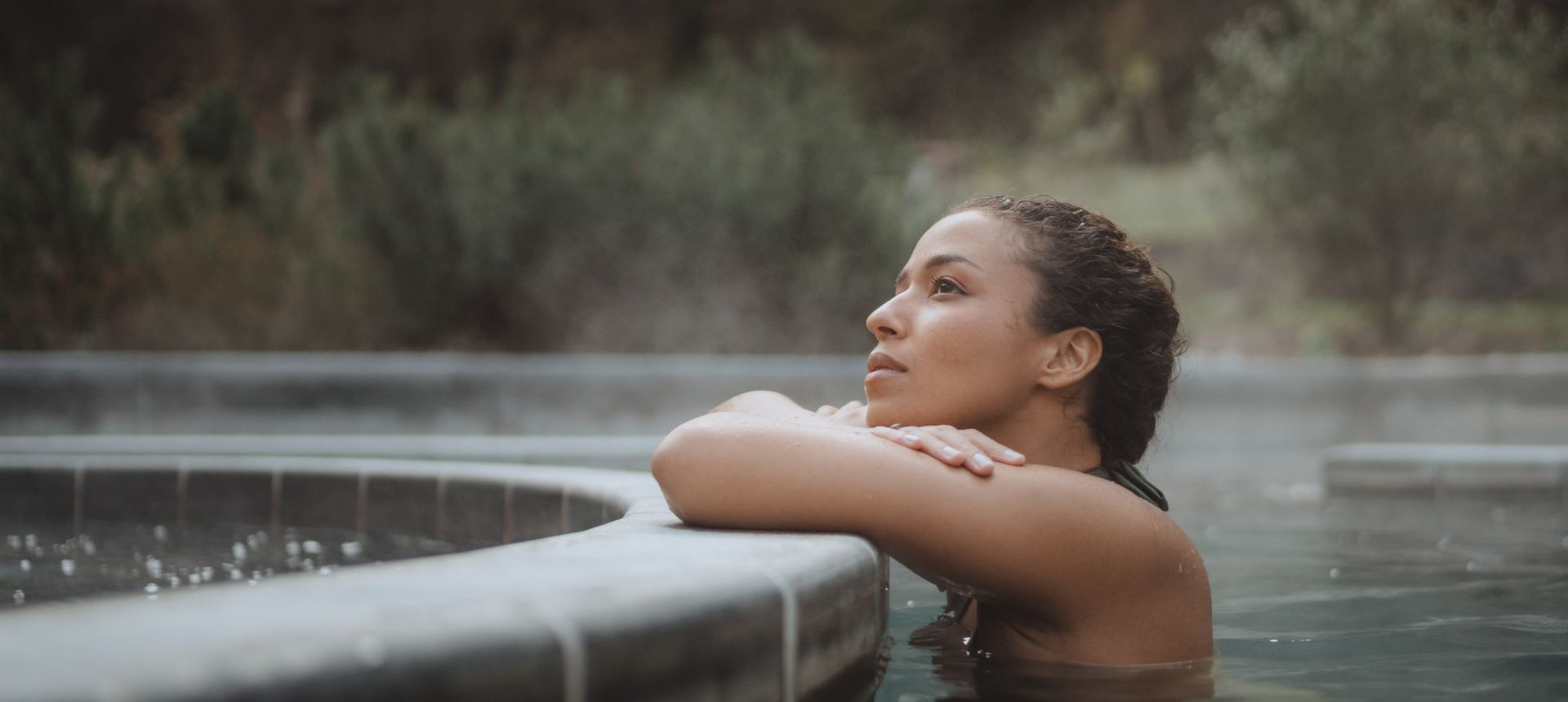 Femme détendue dans un bassin d'eau thermale chaude extérieur